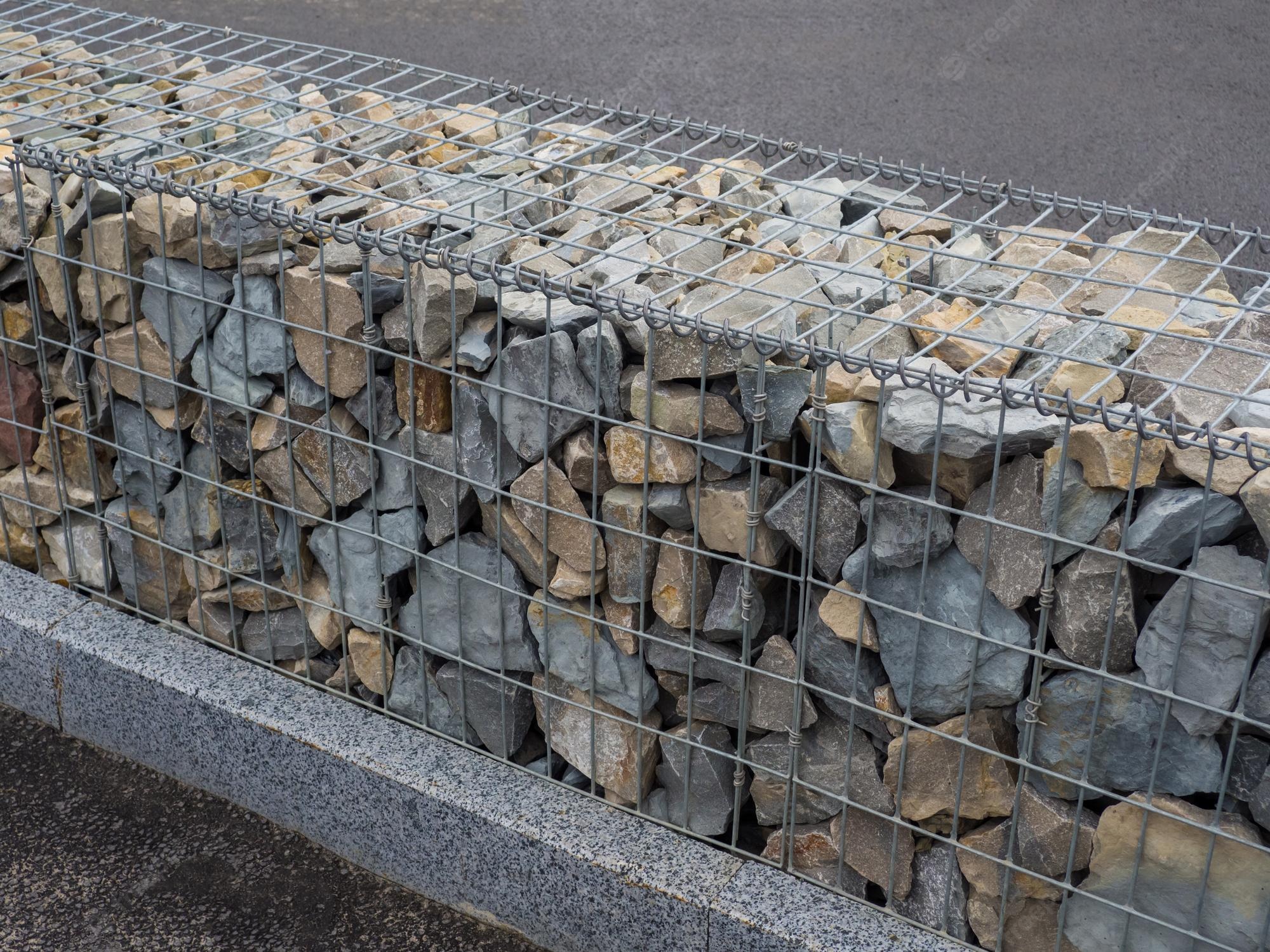 decorative-fence-of-bulk-stone-in-the-grid-textured-background-of-a-stone-wall-with-iron-netting-stone-wall-in-wire-frame-gabion-filled-with-limestone_358403-1123.jpeg